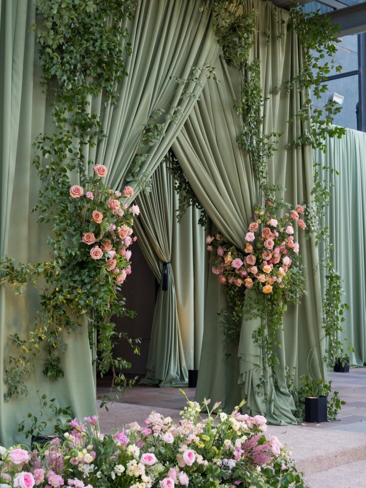 Sage green draped ceremony arch with roses