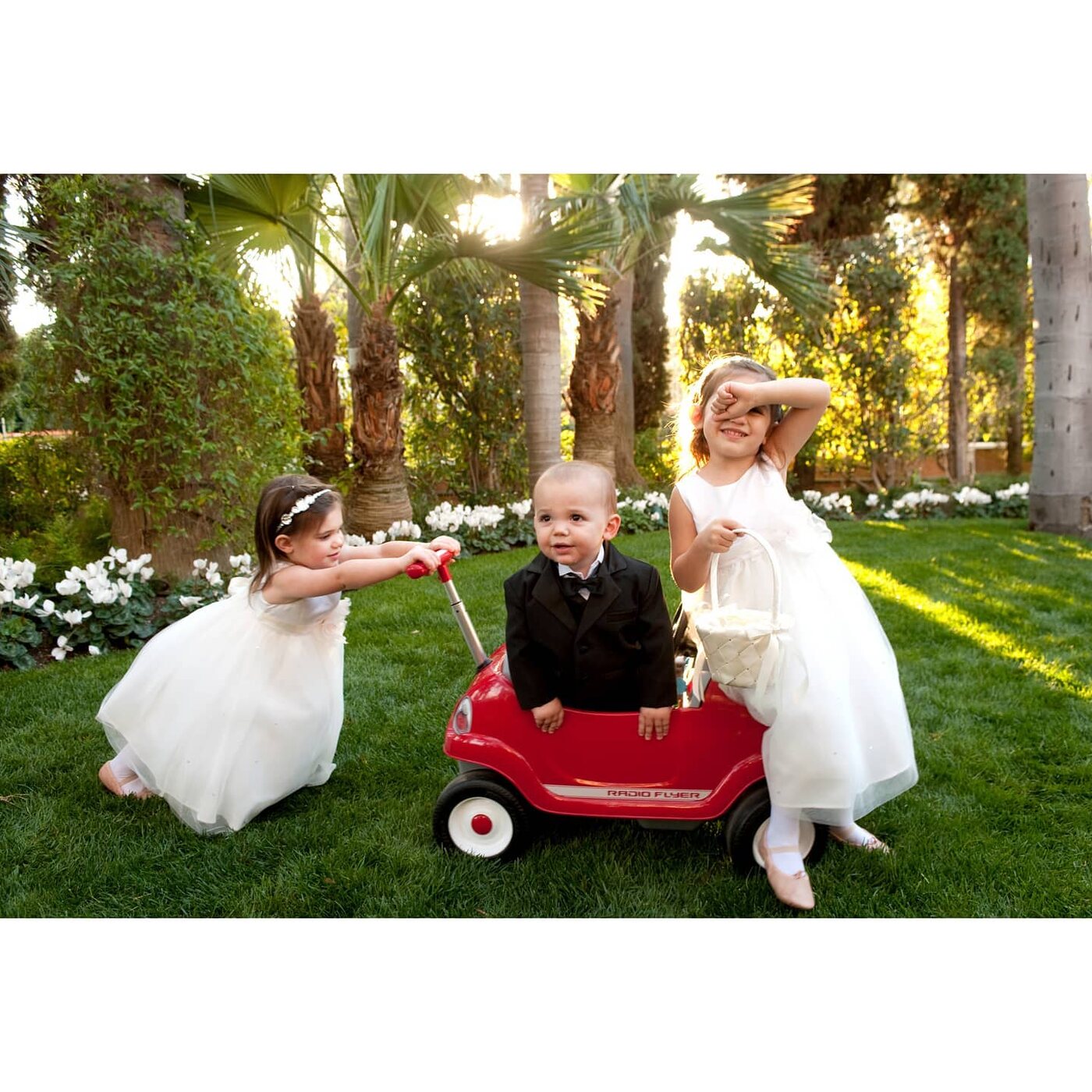Flower children playing on the lawn in a red wagon